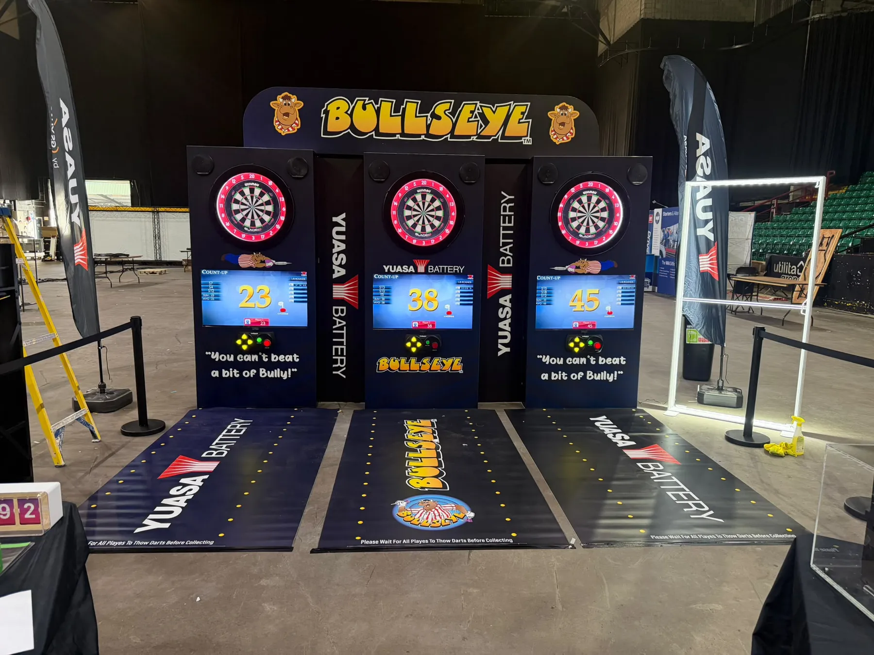 Three-lane branded interactive darts wall with custom header, cabinets and throw mats on a Yuasa exhibition stand